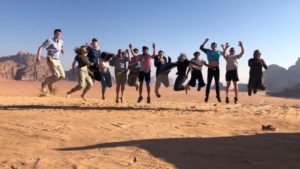 group of friends caught jumping in midair in Jordanian desert.