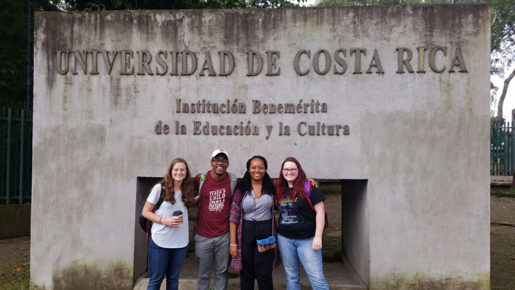 Kerry Johnson with three friends standing in front of University of Costa Rica Sign
