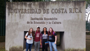 Kerry Johnson with three friends standing in front of University of Costa Rica Sign